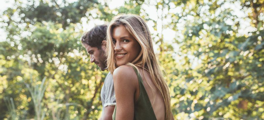 Portrait of attractive young woman walking with her boyfriend outdoors. Young couple together out in countryside.